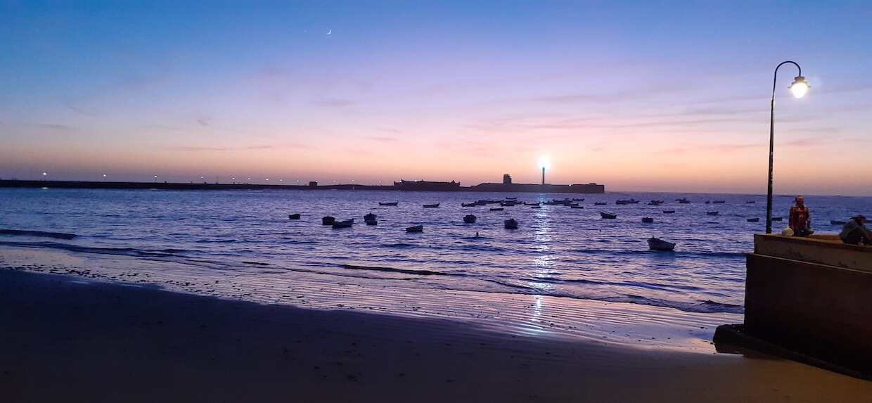 Cadiz Sonnenuntergang am Meer mit Leuchtturm im Hintergrund